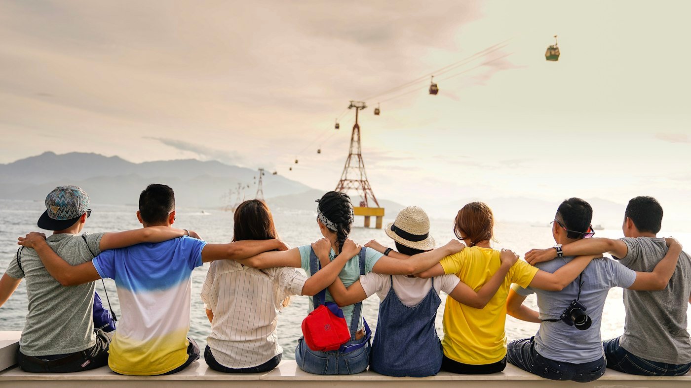 Neighbors sitting together outdoors with arms around each other